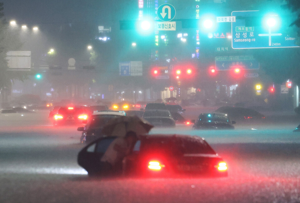 8일 밤 서울 강남구 대치역 인근 도로에서 차량이 침수되자 운전자가 대피하고 있다.  ⓒ연합뉴스