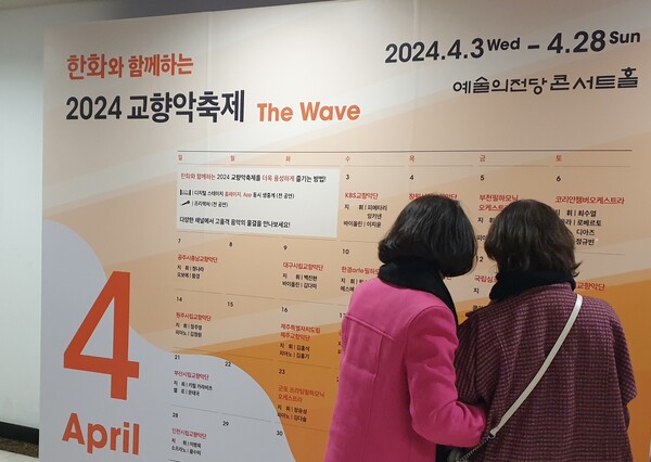 예술의전당은 4월 3일 KBS교향악단 개막 공연을 시작으로 23일 간 ‘한화와 함께하는 2024 교향악축제’를 선보인다. 예술의전당을 찾은 관객들이 교향악축제 공연 안내판을 보고 있다. ⓒ민병무 기자